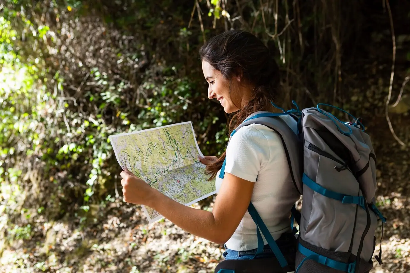Side profile of a woman on a nature adventure using a map.